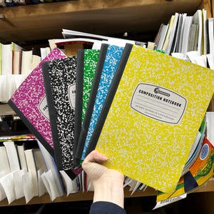 May include: A set of five composition notebooks with a speckled pattern in yellow, blue, green, black, and pink. Each notebook features a black spine and a white label on the front cover with the text Rosmonde Composition Notebook 100 sheets.