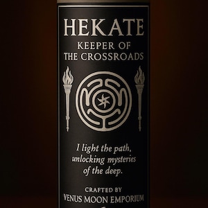Op de afbeelding: Een cilindrische kaars in een glazen pot. Het zwarte etiket bevat de naam "HEKATE" en de tekst "KEEPER OF THE CROSSROADS". Het bevat een labyrintsymbool en de woorden "I light the path, unlocking mysteries of the deep." Gemaakt door Venus Moon Emporium.