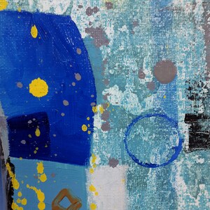 May include: Abstract painting with blue, yellow and grey paint splatters on a textured canvas. The painting features geometric shapes and a circular design.