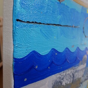May include: Abstract painting featuring blue, turquoise, and white paint. The paint is applied in thick strokes, creating a textured surface. The painting is framed and ready to hang.