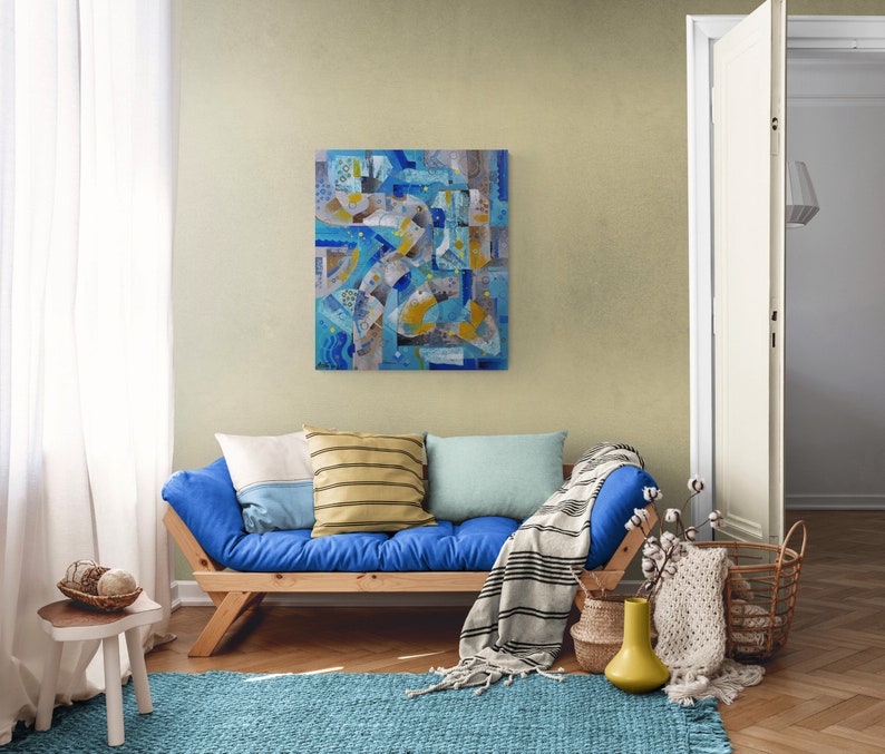 May include: A blue futon sofa with a white, yellow, and blue abstract painting on the wall behind it. The futon has a white, yellow, and blue striped throw pillow and a blue throw blanket.
