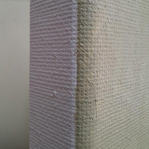 May include: A side view of a rectangular canvas stretched over a wooden frame. The canvas surface features a light beige, textured paint application with visible brushstrokes, while the side edge shows a clean, white, woven fabric texture.
