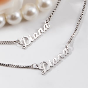 May include: Two silver necklaces with the name "Diana" written in cursive on each pendant.