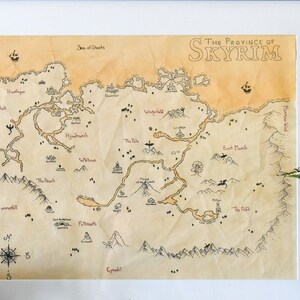 May include: A framed map of the province of Skyrim, a fictional region from the video game series The Elder Scrolls. The map is printed on parchment-like paper and features a detailed depiction of the region's geography, including mountains, rivers, and cities. The map is displayed on a shelf with a decorative skull, miniature figurines, and dice.