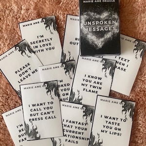 Puede incluir: Una baraja de cartas de oráculo "Unspoken Messages" de "Marie Ame Oracle". Las cartas presentan frases como "I'm secretly in love with you" y "I want to taste you on my lips!" con un diseño de llama.