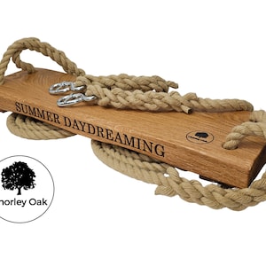 May include: A wooden swing set with rope handles and the words "SUMMER DAYDREAMING" engraved on the seat. The swing is made by Chorley Oak.