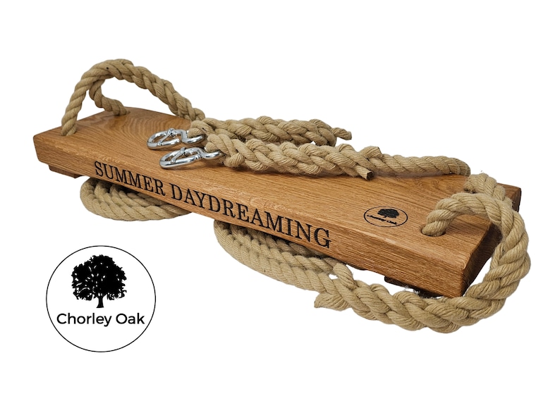 May include: A wooden swing set with rope handles and the words "SUMMER DAYDREAMING" engraved on the seat. The swing is made by Chorley Oak.