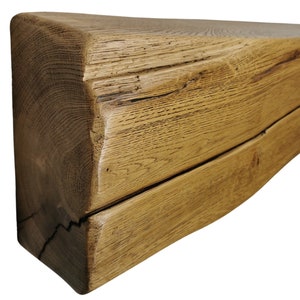 May include: A rustic, reclaimed wood mantel shelf with a natural, brown finish. The shelf has a unique, irregular shape and shows signs of age and wear.