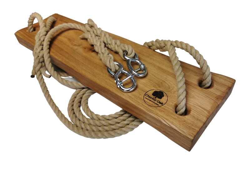 May include: A wooden swing set with two rope loops and metal hooks. The swing is made of natural wood and has a brown finish. The rope is natural colored and is tied to the swing with metal hooks. The swing is labeled "Charley Oak" in the center.