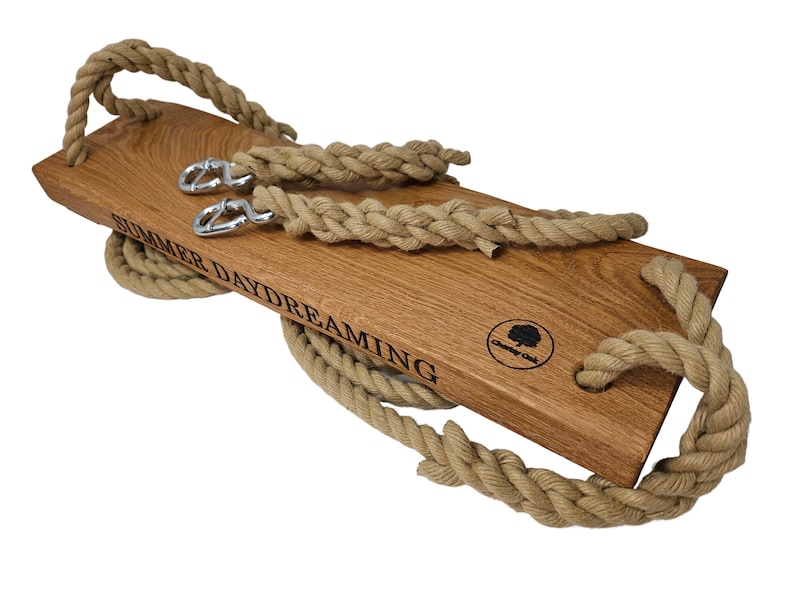 May include: A wooden swing set with natural rope and metal hooks. The swing is engraved with the text "Summer Daydreaming" and a logo.
