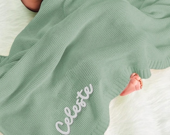 May include: A soft, sage green knitted baby blanket with the name "Celeste" embroidered in white.