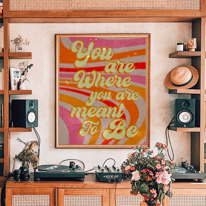May include: A retro-style poster with a colourful, wavy background. The text on the poster reads "You are where you are meant to be".