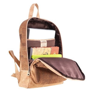 May include: A brown cork backpack with a zippered opening. The backpack is open and has a laptop, books, and a brown lining inside.