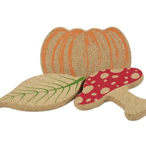 May include: Set of three cork coasters featuring a pumpkin, a leaf, and a mushroom. The pumpkin is orange, the leaf is green, and the mushroom is red with white dots.