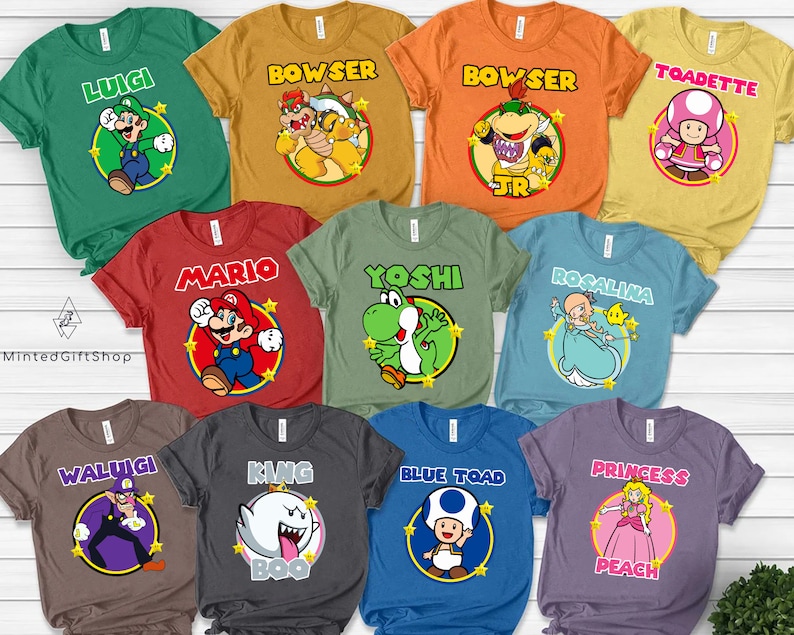 May include: Ten different colored t-shirts with various Super Mario characters printed on them. The characters include Luigi, Bowser, Toad, Mario, Yoshi, Rosalina, Waluigi, King Boo, Blue Toad, and Princess Peach.