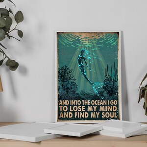 May include: A vintage-style poster featuring a mermaid swimming in the ocean. The mermaid is outlined in black and has a glowing blue tail. The poster has the text "And into the ocean I go to lose my mind and find my soul."