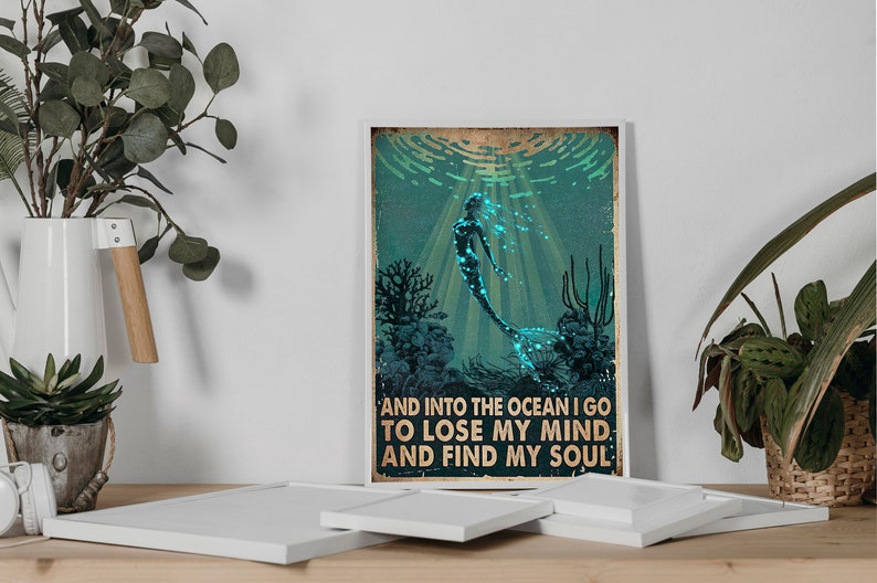 May include: A vintage-style poster featuring a mermaid swimming in the ocean. The mermaid is outlined in black and has a glowing blue tail. The poster has the text "And into the ocean I go to lose my mind and find my soul."