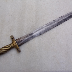 May include: A brass-handled sword with a long, straight blade. The blade is dull and has a patina. The handle is decorated with a spiral pattern.