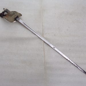 May include: A silver sword with a decorative, pierced, and ornate hilt. The sword has a long, straight blade.