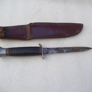 May include: A brown leather sheath with a silver and black handled knife. The knife has a plain blade.