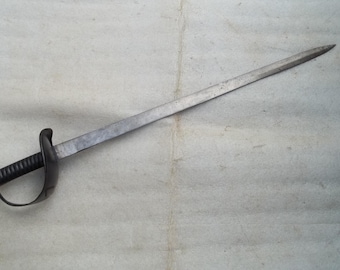 May include: A long, antique sword with a slightly curved blade. The sword features a black handle with a hand guard. The blade has a dull, metallic finish, and the overall design suggests a historical or collectible item.