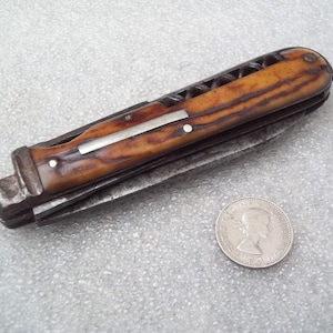 Könnte beinhalten: Ein Vintage-Taschenmesser mit einem braunen und weißen Knochengriff und einer Klinge aus Metall. Das Messer hat einen Korkenzieher und andere Werkzeuge.