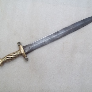 May include: A brass-handled sword with a long, straight blade. The handle is decorated with a spiral pattern and has a round pommel.