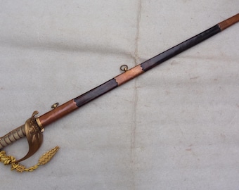 May include: A brown and black sword with a gold hilt and a gold tassel. The sword has a leather grip and a metal scabbard.