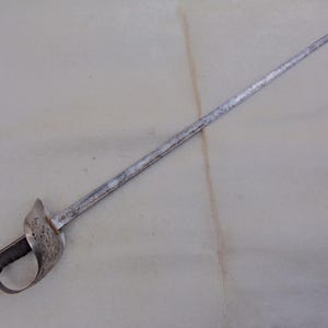 May include: A silver sword with a decorative hilt and a long, straight blade. The sword is in good condition, with some signs of wear and tear.