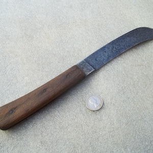 May include: A brown handled knife with a curved blade. The blade is made of metal and has a dull finish.