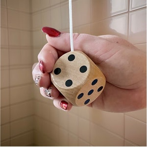 May include: A wooden light switch pull with a dice design. The dice is brown with black dots and shows the number five.