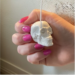 May include: White ceramic skull light pull. The skull has a detailed design with visible teeth and eye sockets.