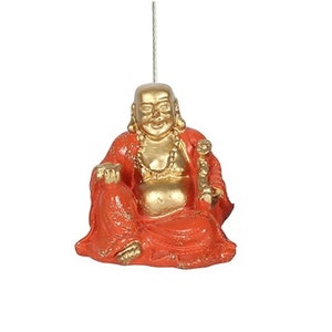 May include: A gold and orange figurine of a smiling Buddha sitting with his legs crossed. He is wearing a red robe and has a gold necklace and a gold staff in his hand.