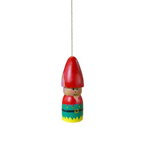 May include: A wooden pull chain with a painted gnome design. The gnome is wearing a red hat, green pants, and a yellow belt.