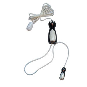 May include: A whimsical light pull featuring a penguin design. The pull has a black and white penguin figure with a white cord and a white, oval-shaped handle. The penguin figure is made of wood and has a cute, cartoonish appearance.