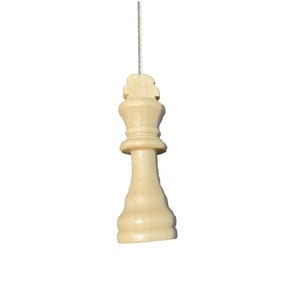 May include: A wooden light brown chess piece shaped like a king, hanging from a white string.