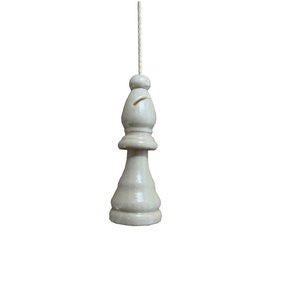 May include: A white wooden chess piece shaped like a pawn, used as a pull chain for a light fixture.