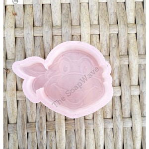 May include: Pink silicone mold of a Teenage Mutant Ninja Turtle's head. The mold has a textured surface and the words "The Soap Wave" are printed on the side.