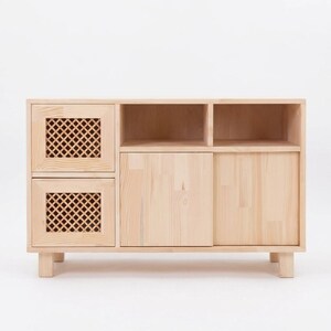 May include: A light-colored wooden sideboard featuring two stacked drawers on the left with lattice-patterned fronts, two open storage compartments on the top right, and two solid-front cabinet doors on the bottom right, supported by four legs.