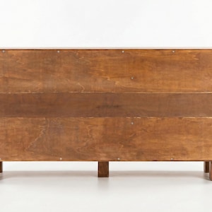 May include: A wooden cabinet with a warm brown finish. The cabinet has a rectangular shape with a series of horizontal wooden panels. It stands on four short, square legs. The wood grain is visible, adding texture to the piece.