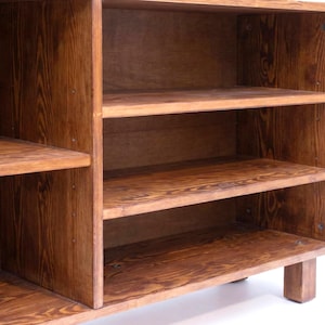 May include: A wooden cabinet with multiple shelves. The cabinet is made of a warm-toned wood, with visible grain patterns. The shelves are evenly spaced, providing storage space. The cabinet is designed for storage and display.