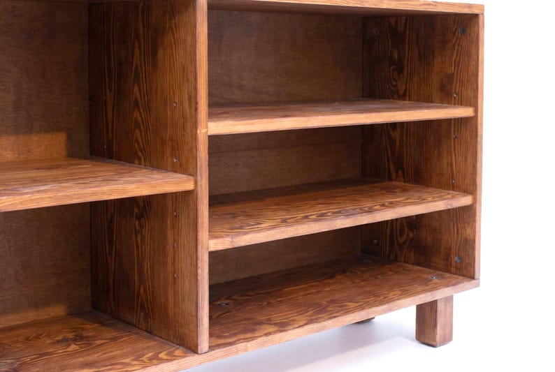 May include: A wooden cabinet with multiple shelves. The cabinet is made of a warm-toned wood, with visible grain patterns. The shelves are evenly spaced, providing storage space. The cabinet is designed for storage and display.