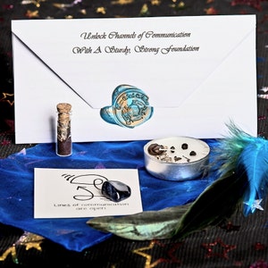 May include: A collection of spiritual items: a sealed white envelope with text, a small glass vial, a tealight candle, a blue feather, and a black stone. The envelope reads "Unlock Channels of Communication With A Sturdy, Strong Foundation."