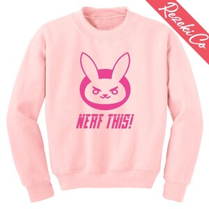 Puede incluir: Sudadera rosa con un gráfico de conejo rosa y el texto "NERF THIS!"