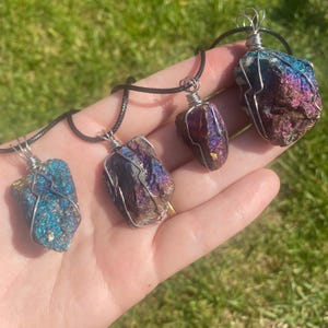 May include: Four iridescent pyrite crystal pendants on black cords. Each crystal is wrapped in silver wire and has a unique shape and colour.