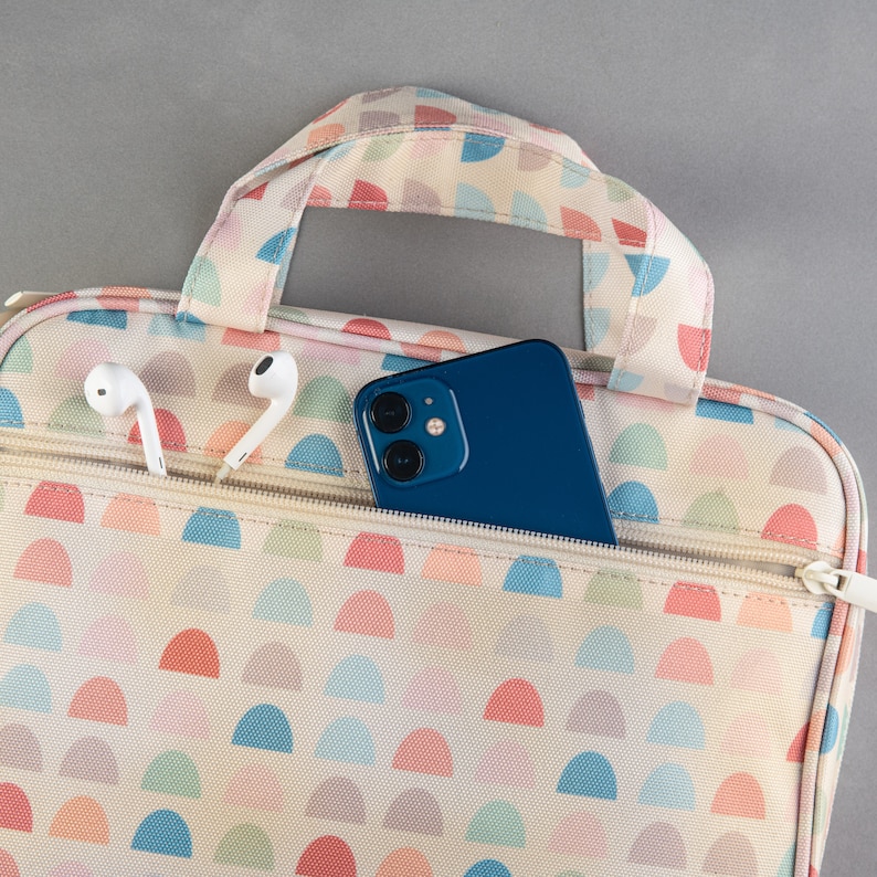 May include: A white and pink patterned zippered pouch with a blue phone and white earbuds inside.