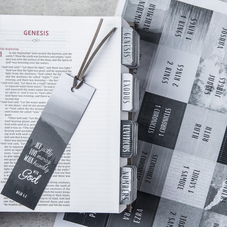 May include: A close-up of a black and white bookmark with a forest scene and the text "Act justly, love mercy, walk humbly with God". The bookmark is placed in a Bible with tabs for each book of the Bible.
