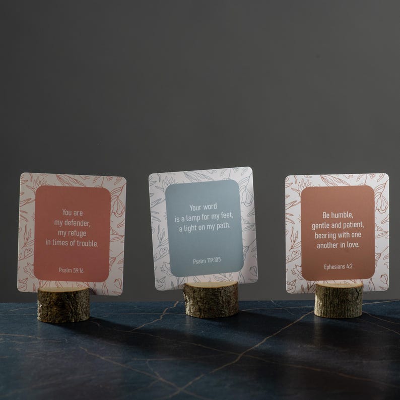 Pu&ograve; includere: Tre portacarte decorativi in legno con citazioni ispiratrici. Ogni carta ha uno sfondo di colore diverso e un design floreale. Il testo sulle carte include versetti biblici dai Salmi e dagli Efesini.