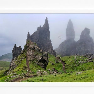 Peut inclure: Un paysage brumeux avec de hautes formations rocheuses dentelées s'élevant d'une colline herbeuse. Les rochers sont enveloppés de brouillard, créant une scène dramatique et éthérée.