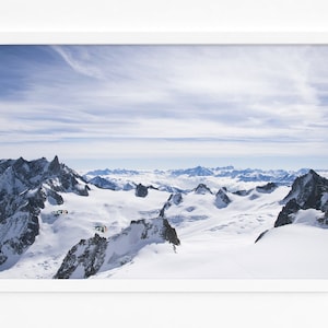 Puede incluir: Una vista panorámica de montañas cubiertas de nieve con un cielo azul claro y nubes blancas. Las montañas están cubiertas de nieve y hielo, y el cielo es de un azul brillante. Las nubes son blancas y esponjosas, y están dispersas por el cielo.
